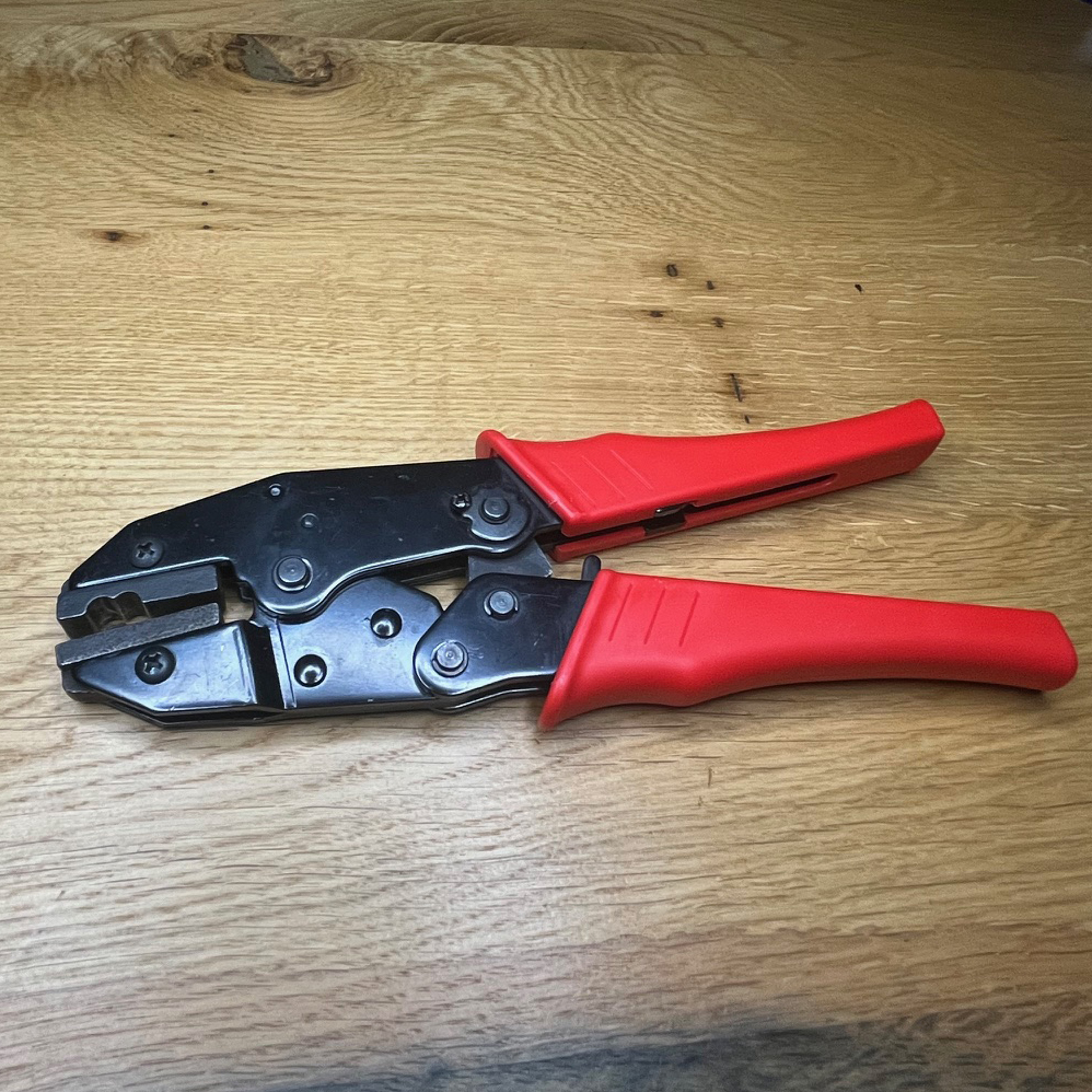 Handverschlusszange mit rotem Griff liegt auf einem Tisch