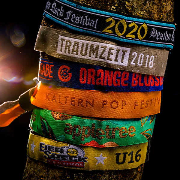 Mehrere gewebte Einlassbänder in verschiedenen Farben um einen Baumstamm gebunden