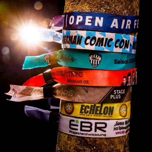 Mehrere bedruckte Stoff-Einlassbänder in verschiedenen Farben um einen Baumstamm gebunden