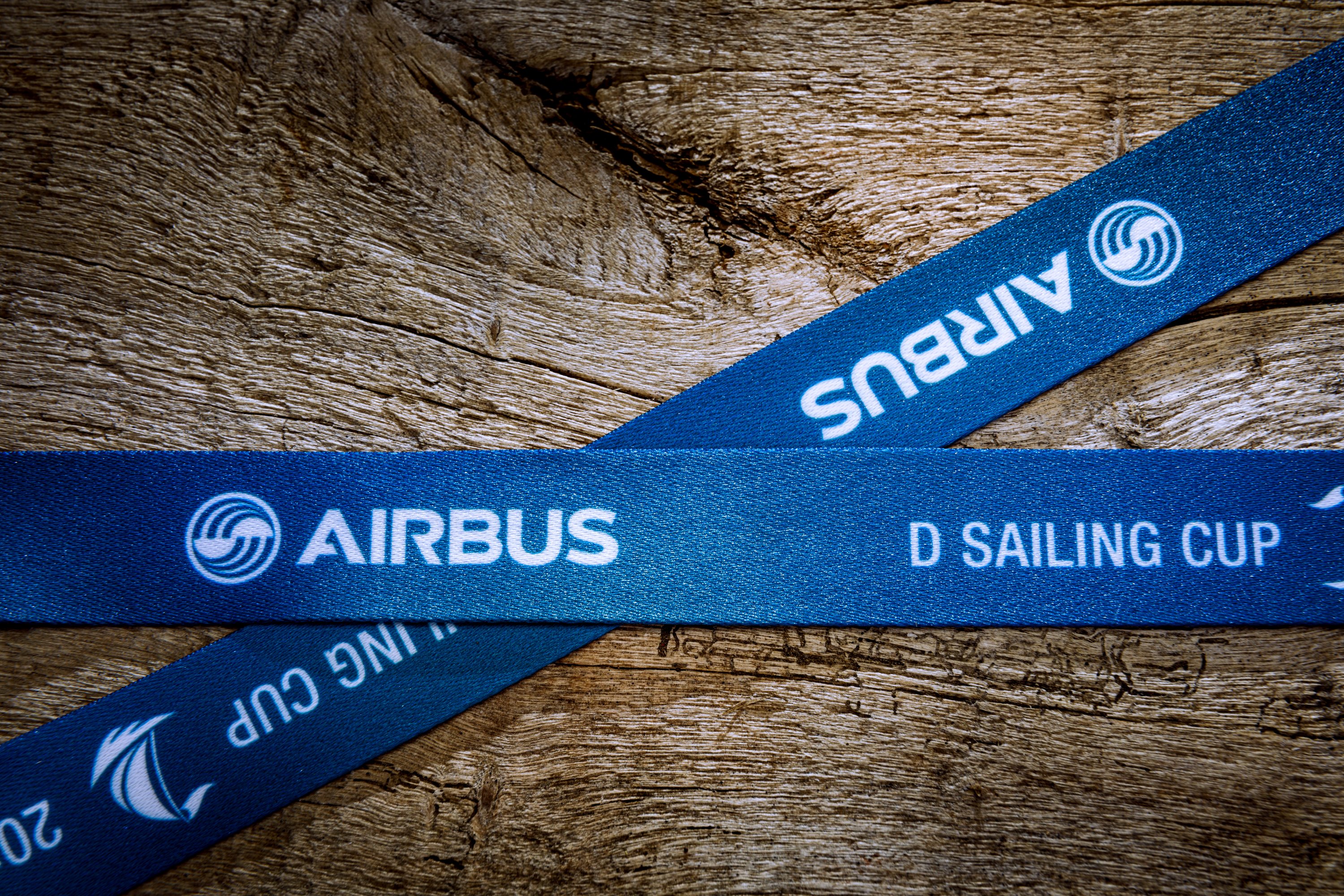 Blaues Schlüsselband aus Satin mit weißem Aufdruck auf Holzoberfläche