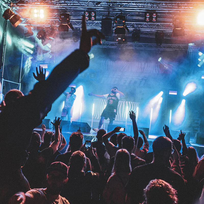 Konzertbesucher feiern vor einer beleuchteten Bühne mit Künstlern