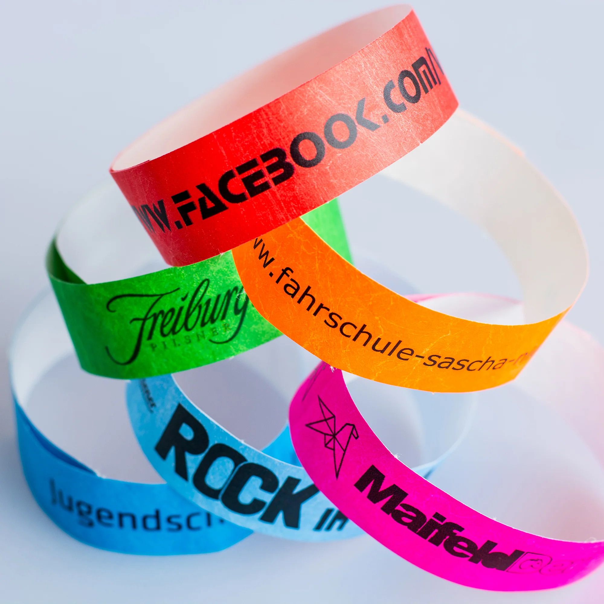 Mehrere bedruckte Tyvek-Einlassbänder in verschiedenen Farben auf hellem Hintergrund