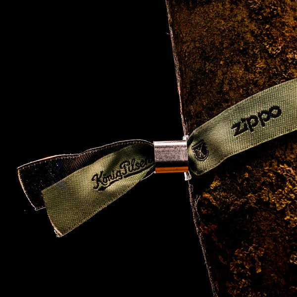 Grünes gewebtes Einlassband mit Metallverschluss an einem Baumstamm