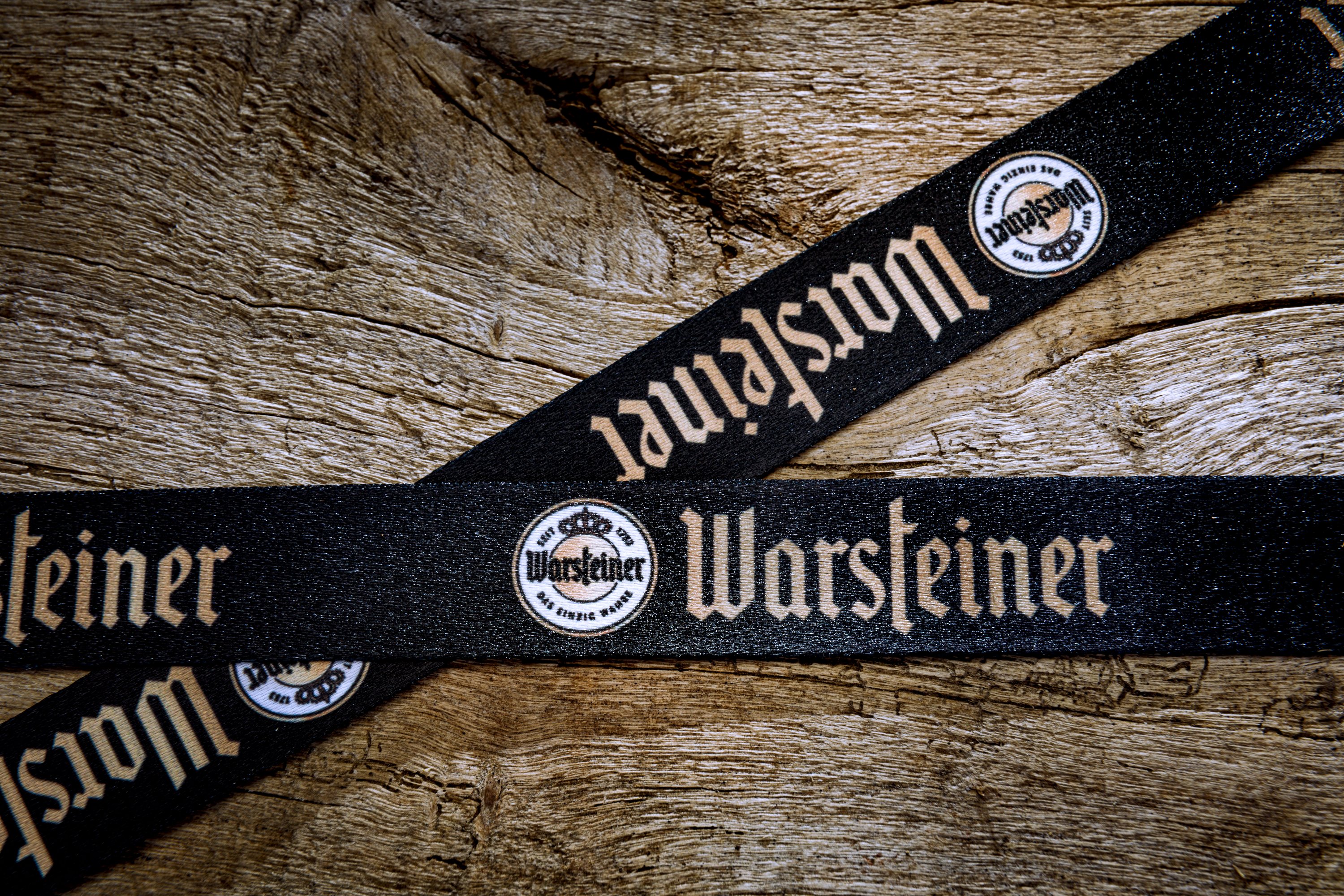 Schwarzes Satin-Schlüsselband mit beigem Aufdruck auf Holzoberfläche